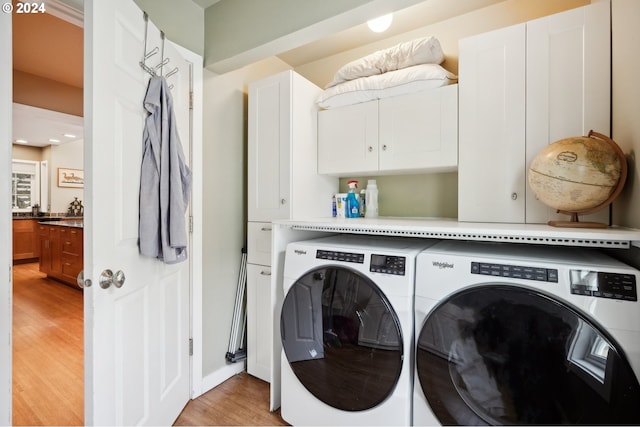 laundry room with light hardwood / wood-style flooring, cabinets, and separate washer and dryer