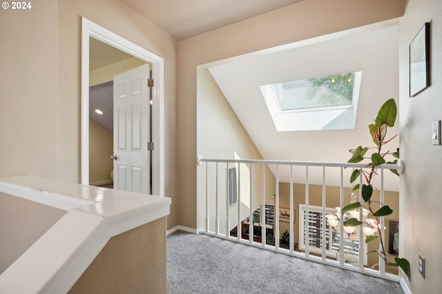 hall with light carpet and vaulted ceiling with skylight