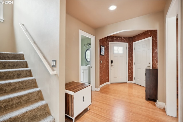 entryway with recessed lighting, arched walkways, light wood-style floors, baseboards, and stairs