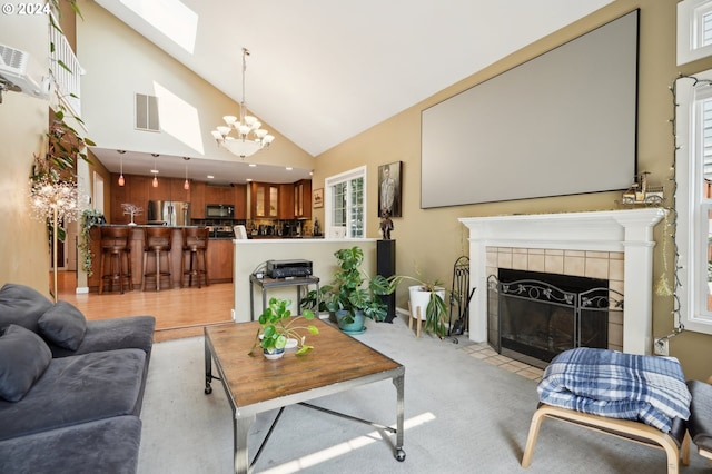 living room with a wealth of natural light, an inviting chandelier, high vaulted ceiling, and a fireplace