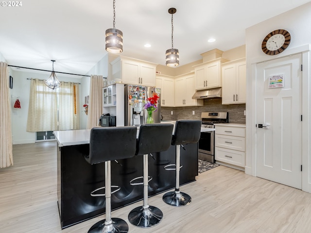 kitchen with pendant lighting, a kitchen island, stainless steel appliances, and light hardwood / wood-style flooring