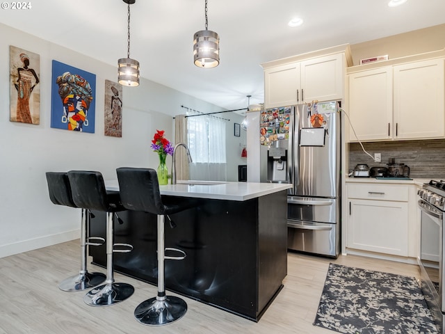 kitchen with pendant lighting, an island with sink, sink, light hardwood / wood-style flooring, and stainless steel appliances