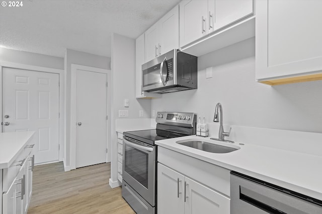 kitchen featuring sink, a textured ceiling, light hardwood / wood-style floors, white cabinetry, and stainless steel appliances