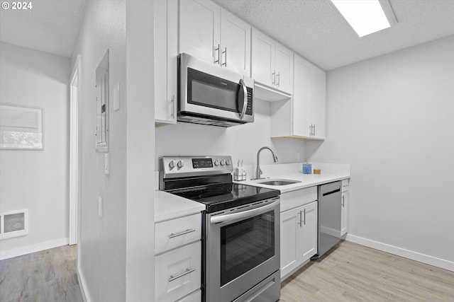 kitchen featuring appliances with stainless steel finishes, a textured ceiling, sink, light hardwood / wood-style flooring, and white cabinets