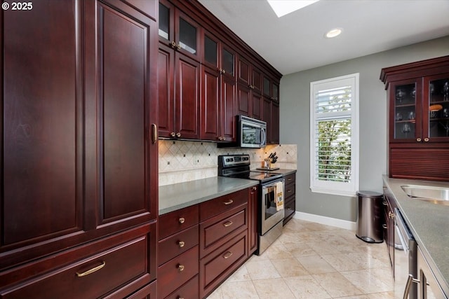 225 S Montgomery St Unit G10, Portland, OR 97201 - kitchen featuring stainless steel appliances, dark brown cabinets, baseboards, tasteful backsplash, and glass insert cabinets
