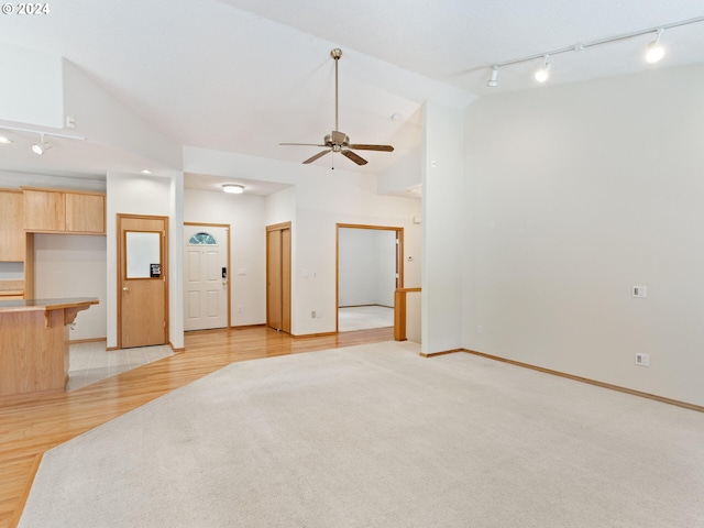 spare room with track lighting, ceiling fan, light hardwood / wood-style floors, and vaulted ceiling