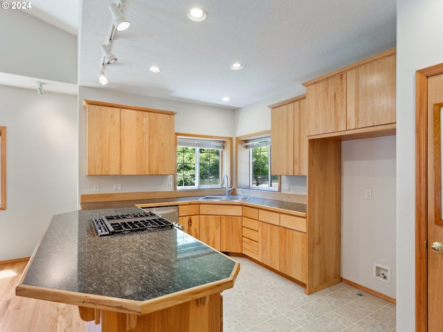 kitchen with light brown cabinets, a textured ceiling, kitchen peninsula, and sink