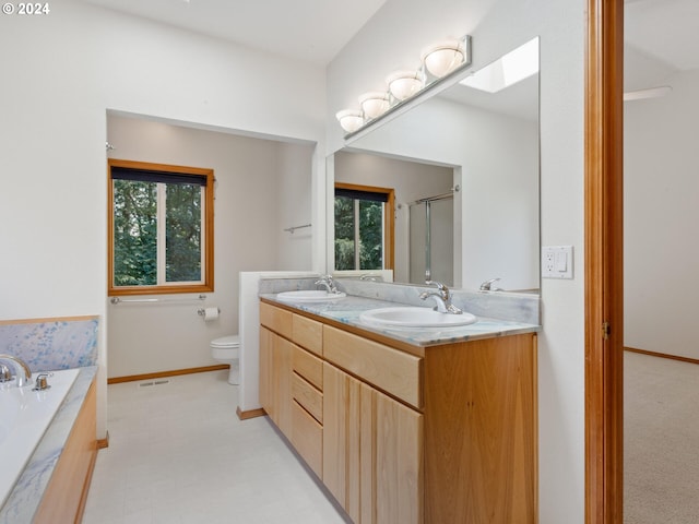 full bathroom with a skylight, toilet, shower with separate bathtub, and vanity