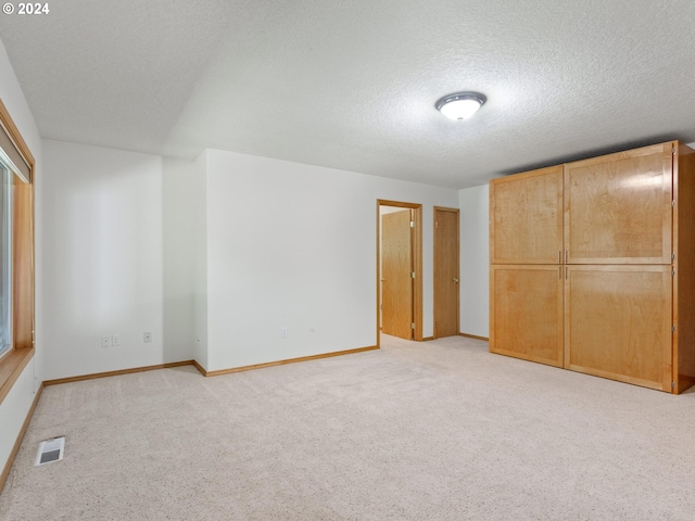 unfurnished bedroom with a textured ceiling, light colored carpet, and a closet