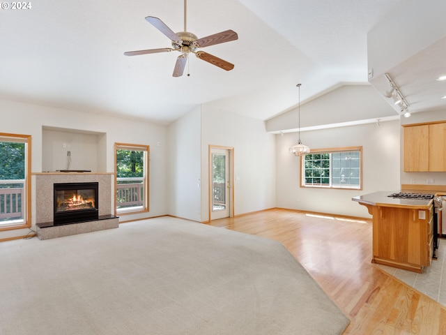 unfurnished living room featuring vaulted ceiling, plenty of natural light, ceiling fan, and light hardwood / wood-style floors