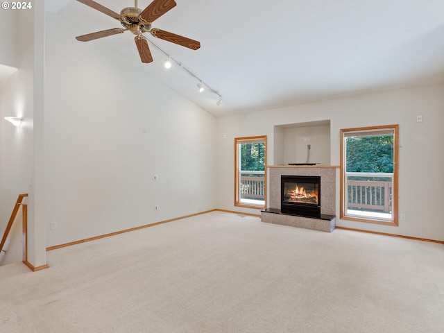 unfurnished living room featuring track lighting, ceiling fan, plenty of natural light, and light carpet