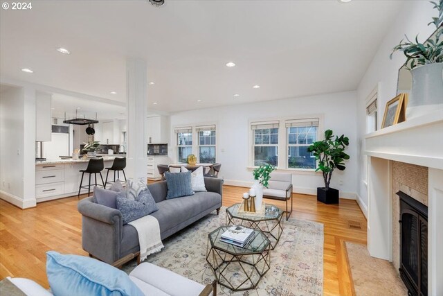 kitchen with white cabinetry, a center island with sink, light wood-type flooring, and appliances with stainless steel finishes