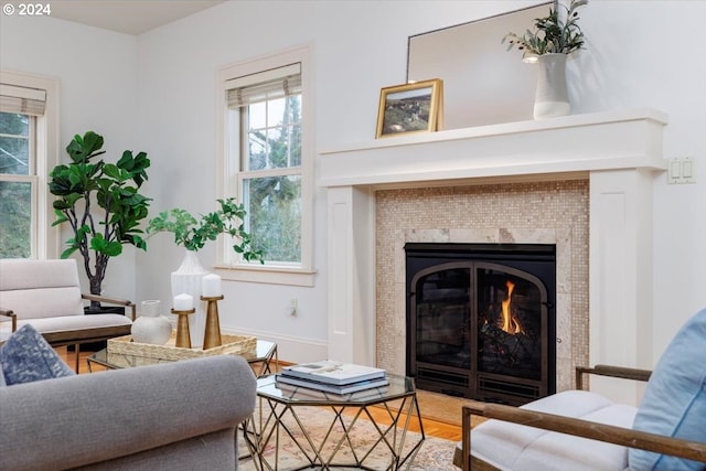 living area with wood-type flooring, a wealth of natural light, and a tiled fireplace