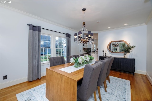 dining space featuring an inviting chandelier, ornamental molding, and light hardwood / wood-style flooring