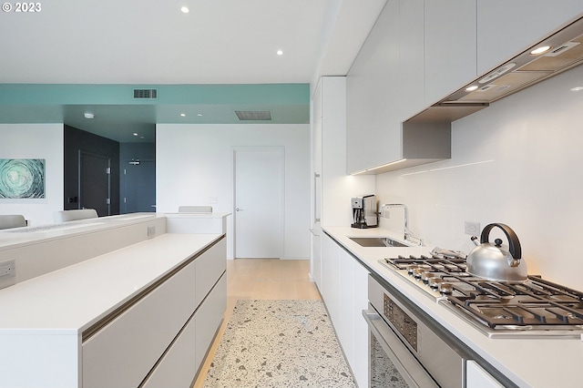 kitchen with white cabinets, light hardwood / wood-style floors, and appliances with stainless steel finishes