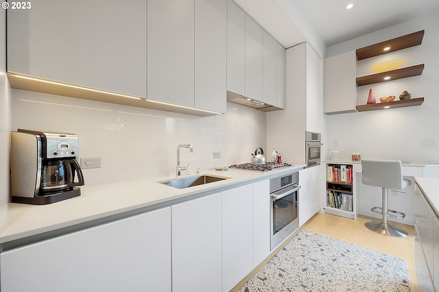 kitchen with light wood-type flooring, white cabinetry, sink, and stainless steel appliances