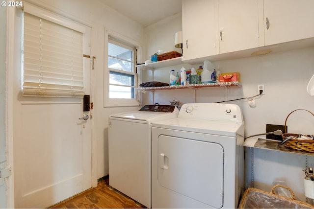 clothes washing area with washer and clothes dryer, cabinets, and hardwood / wood-style floors