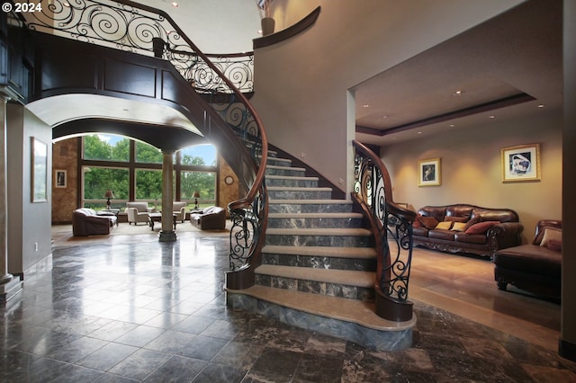 stairway with a raised ceiling and a high ceiling