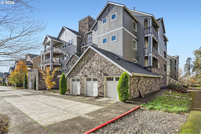 11529 SE Bateleur Way Unit C8, Happy Valley, OR 97086 - view of property exterior featuring stone siding, a garage, concrete driveway, and a balcony