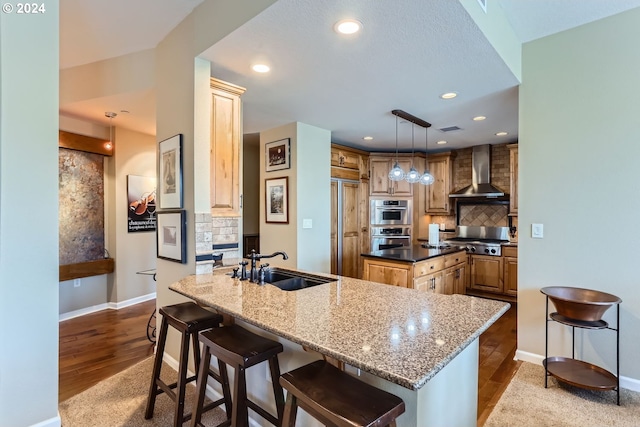 kitchen featuring wall chimney exhaust hood, decorative backsplash, light wood-type flooring, decorative light fixtures, and kitchen peninsula