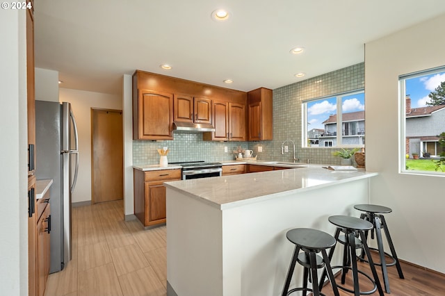 kitchen featuring appliances with stainless steel finishes, a breakfast bar, a wealth of natural light, sink, and kitchen peninsula