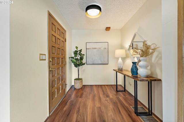 hall featuring dark wood-type flooring and a textured ceiling