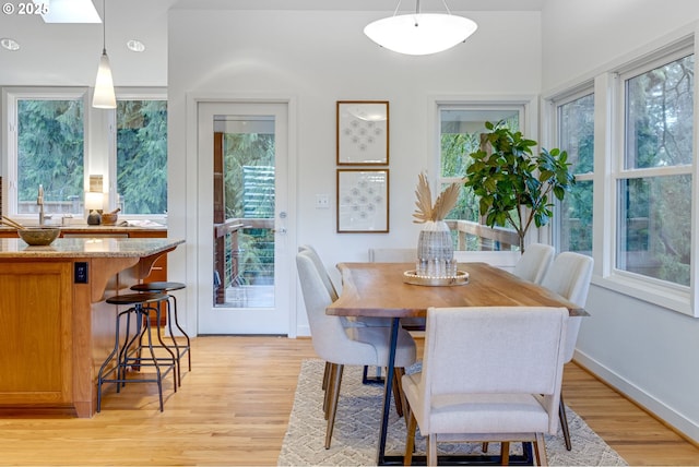 dining area with light wood-type flooring, a healthy amount of sunlight, and sink