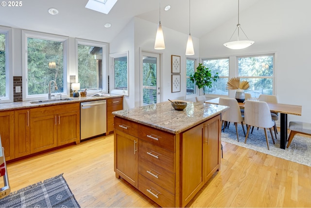 kitchen featuring vaulted ceiling with skylight, a kitchen island, stainless steel dishwasher, sink, and hanging light fixtures