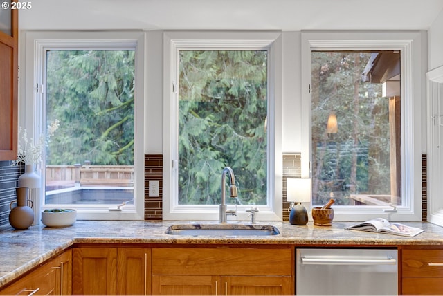 kitchen with light stone countertops, sink, a wealth of natural light, and stainless steel dishwasher