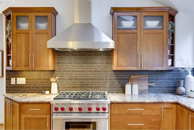 kitchen with tasteful backsplash, light stone countertops, wall chimney exhaust hood, and stainless steel stove