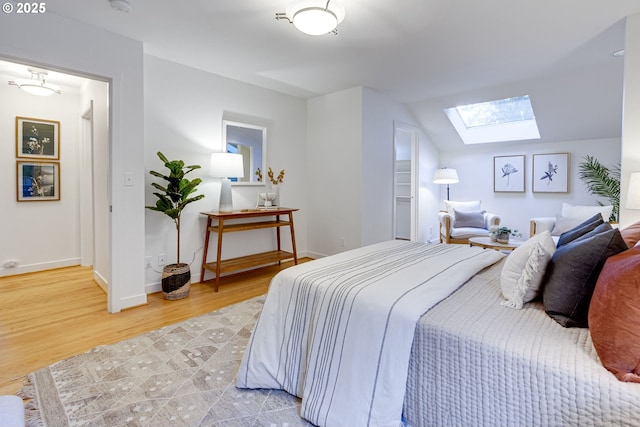 bedroom with hardwood / wood-style flooring and lofted ceiling with skylight