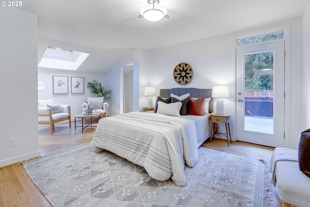 bedroom featuring vaulted ceiling with skylight, wood-type flooring, and access to outside