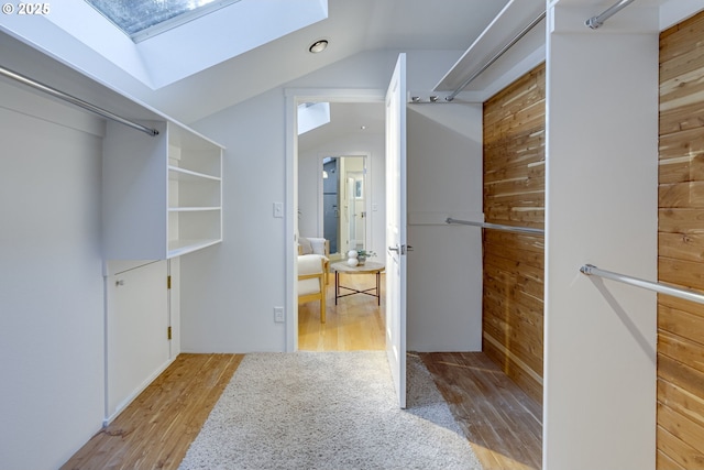 spacious closet with light hardwood / wood-style flooring and lofted ceiling with skylight