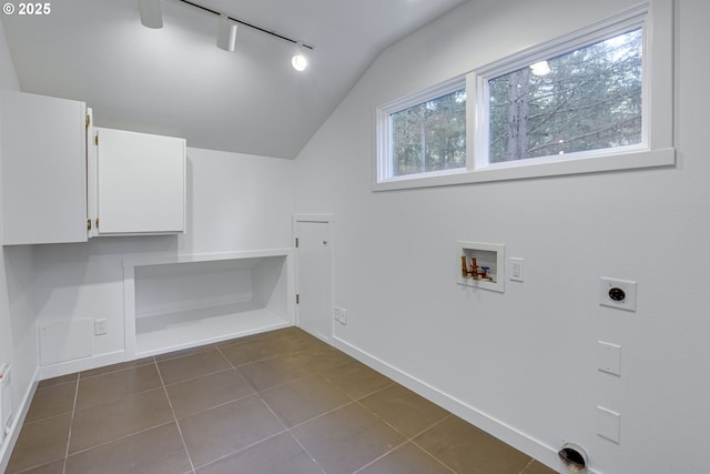 clothes washing area with electric dryer hookup, track lighting, dark tile patterned flooring, hookup for a washing machine, and cabinets