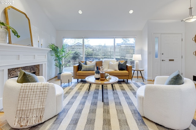 living room featuring light hardwood / wood-style flooring, a high end fireplace, lofted ceiling, and a healthy amount of sunlight