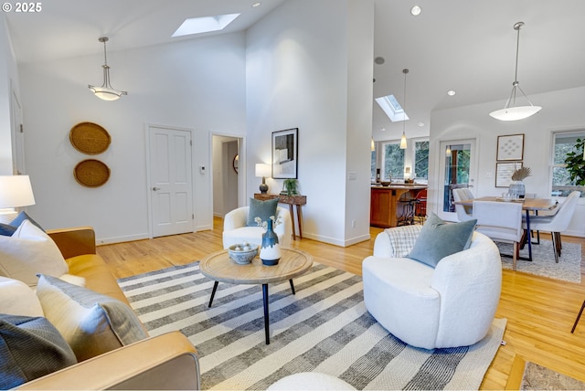 living room with light hardwood / wood-style floors, high vaulted ceiling, and a skylight