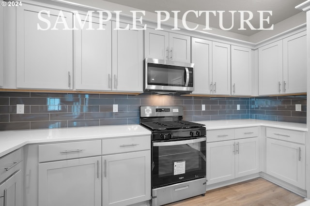 kitchen featuring appliances with stainless steel finishes, backsplash, light hardwood / wood-style floors, and white cabinetry