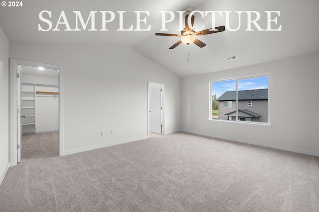 unfurnished bedroom featuring light carpet, a walk in closet, ceiling fan, a closet, and lofted ceiling