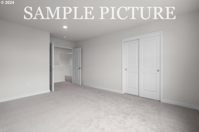 unfurnished bedroom with light carpet and a closet