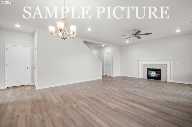 unfurnished living room with ceiling fan with notable chandelier and light hardwood / wood-style flooring