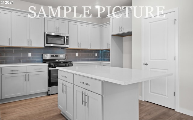 kitchen with tasteful backsplash, a center island, stainless steel appliances, and light hardwood / wood-style floors