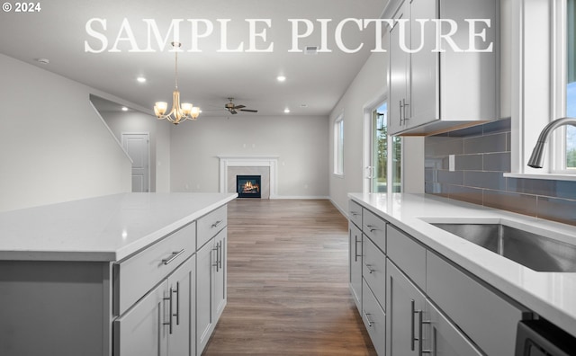 kitchen featuring tasteful backsplash, ceiling fan, sink, hardwood / wood-style flooring, and gray cabinets