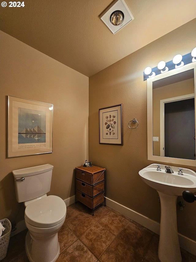 bathroom with toilet, baseboards, and a textured ceiling