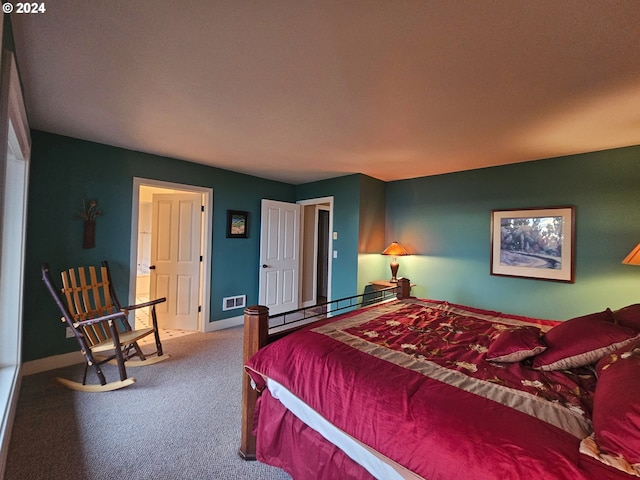 carpeted bedroom featuring a baseboard heating unit, baseboards, and visible vents