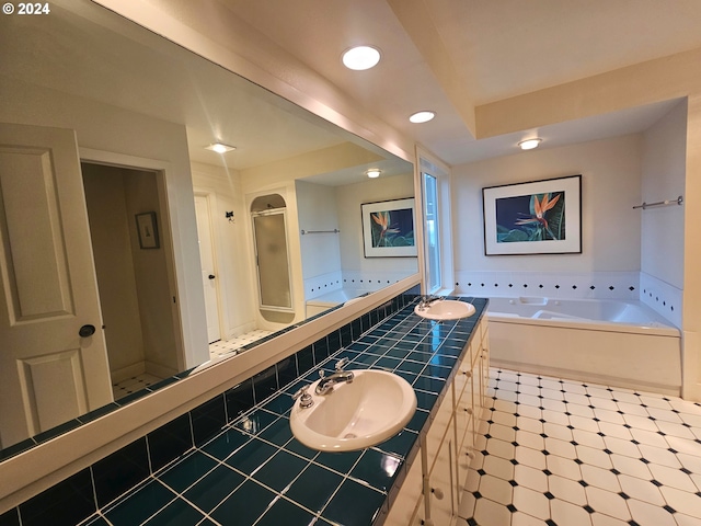 bathroom featuring a bath, a shower stall, and a sink