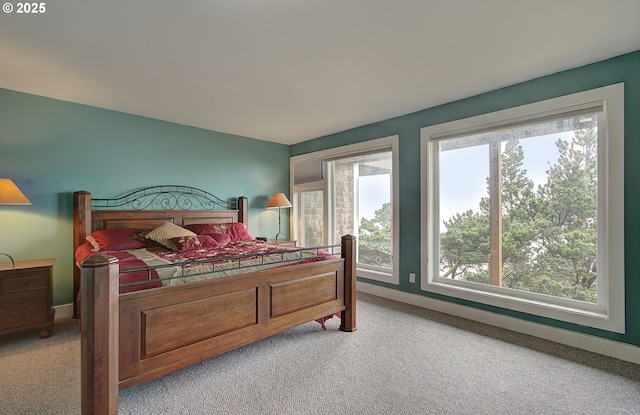 bedroom with baseboards, light carpet, and multiple windows