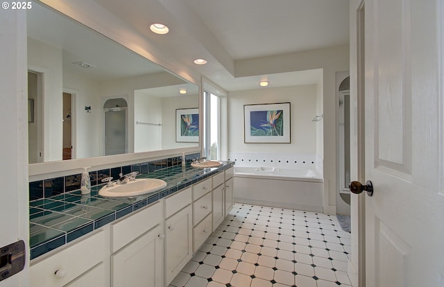 full bath featuring recessed lighting, a stall shower, double vanity, and a sink