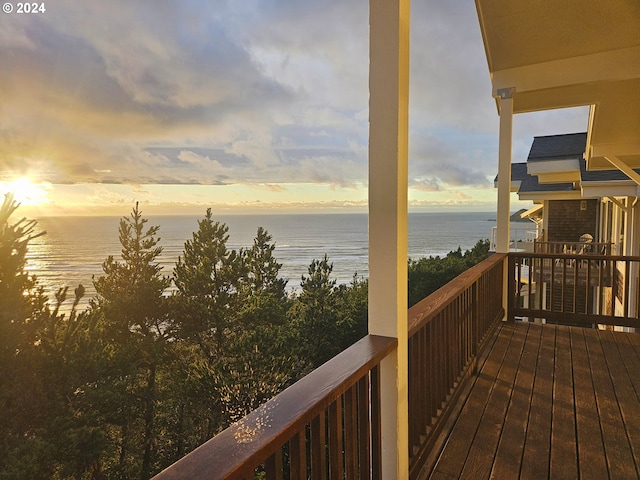 deck at dusk featuring a water view