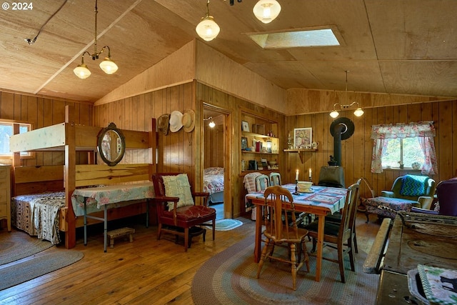 dining room featuring a skylight, wooden walls, hardwood / wood-style floors, and wood ceiling