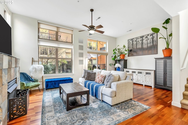 living room with a fireplace, hardwood / wood-style floors, ceiling fan, and a healthy amount of sunlight